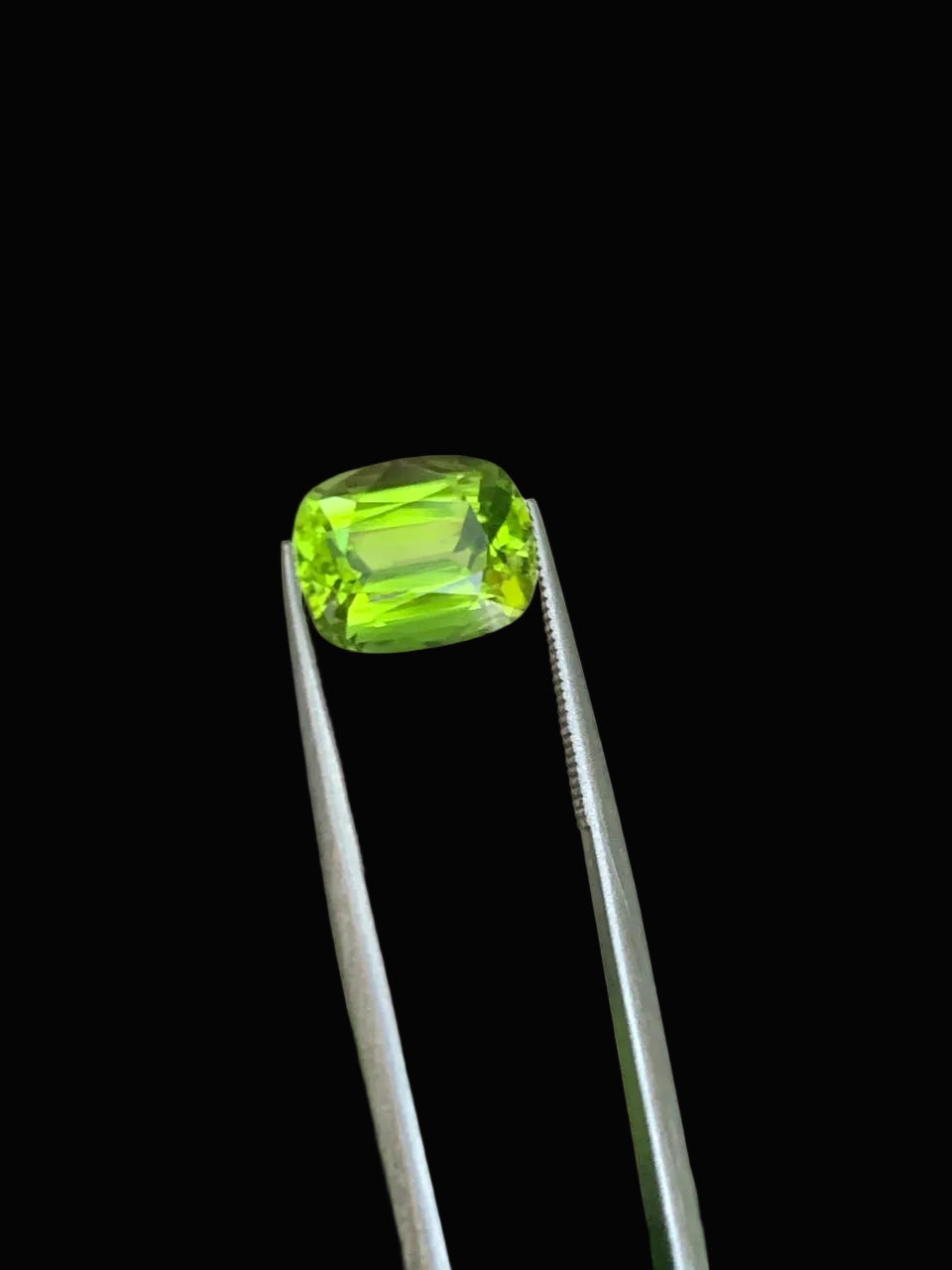 A bright green cushion-cut peridot gemstone 