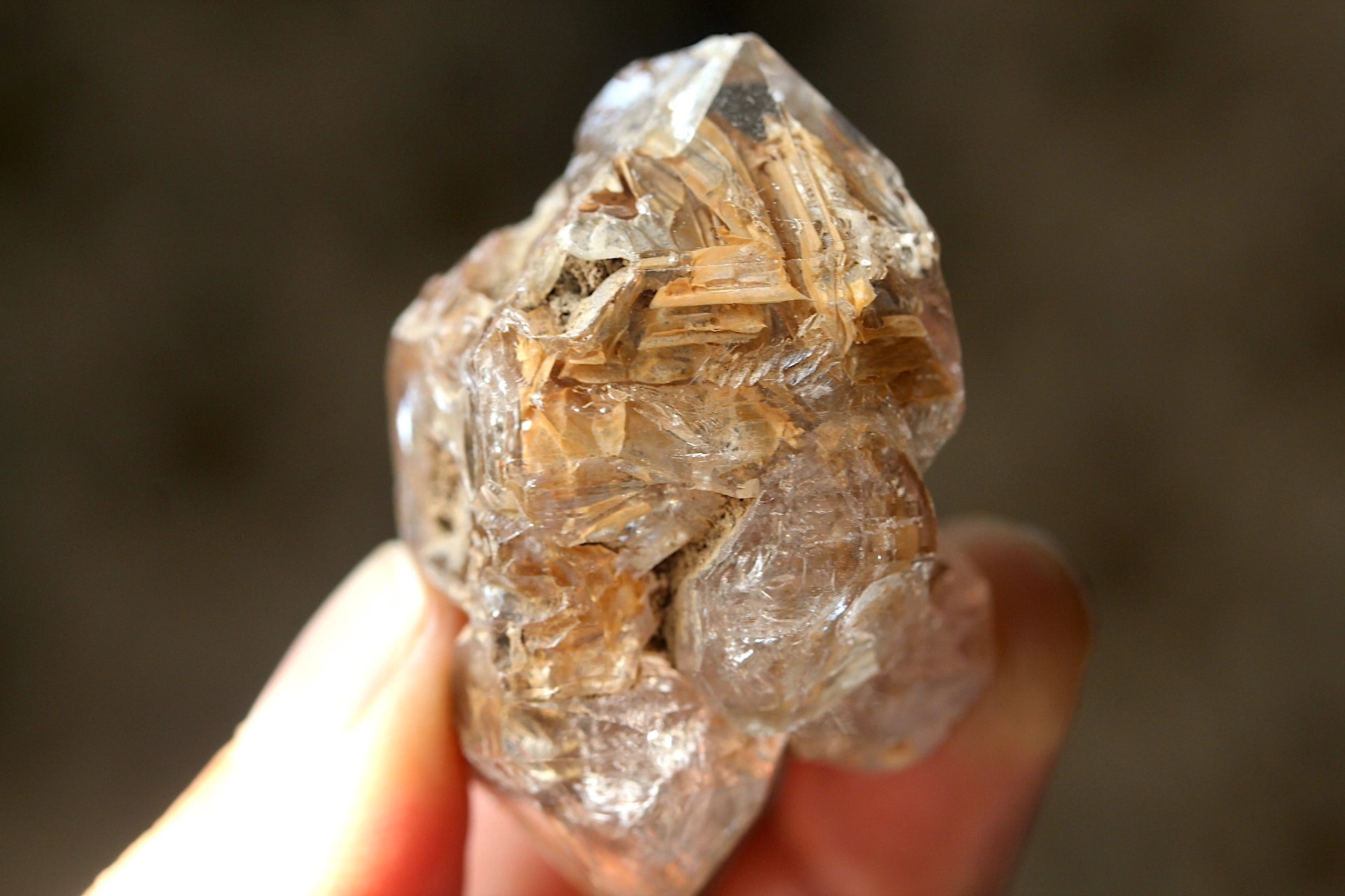 Raw diamond Quartz held in a hand with a blurred background