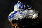 A rough mineral specimen with vivid blue lapis lazuli-like crystals 