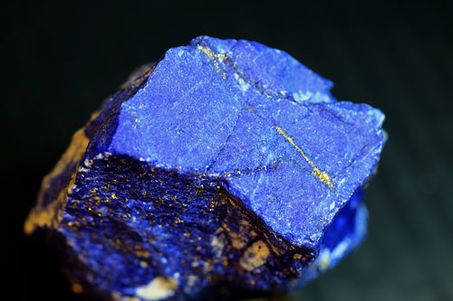 a blue lapis lazuli crystal with visible gold pyrite veins and a dark matrix,