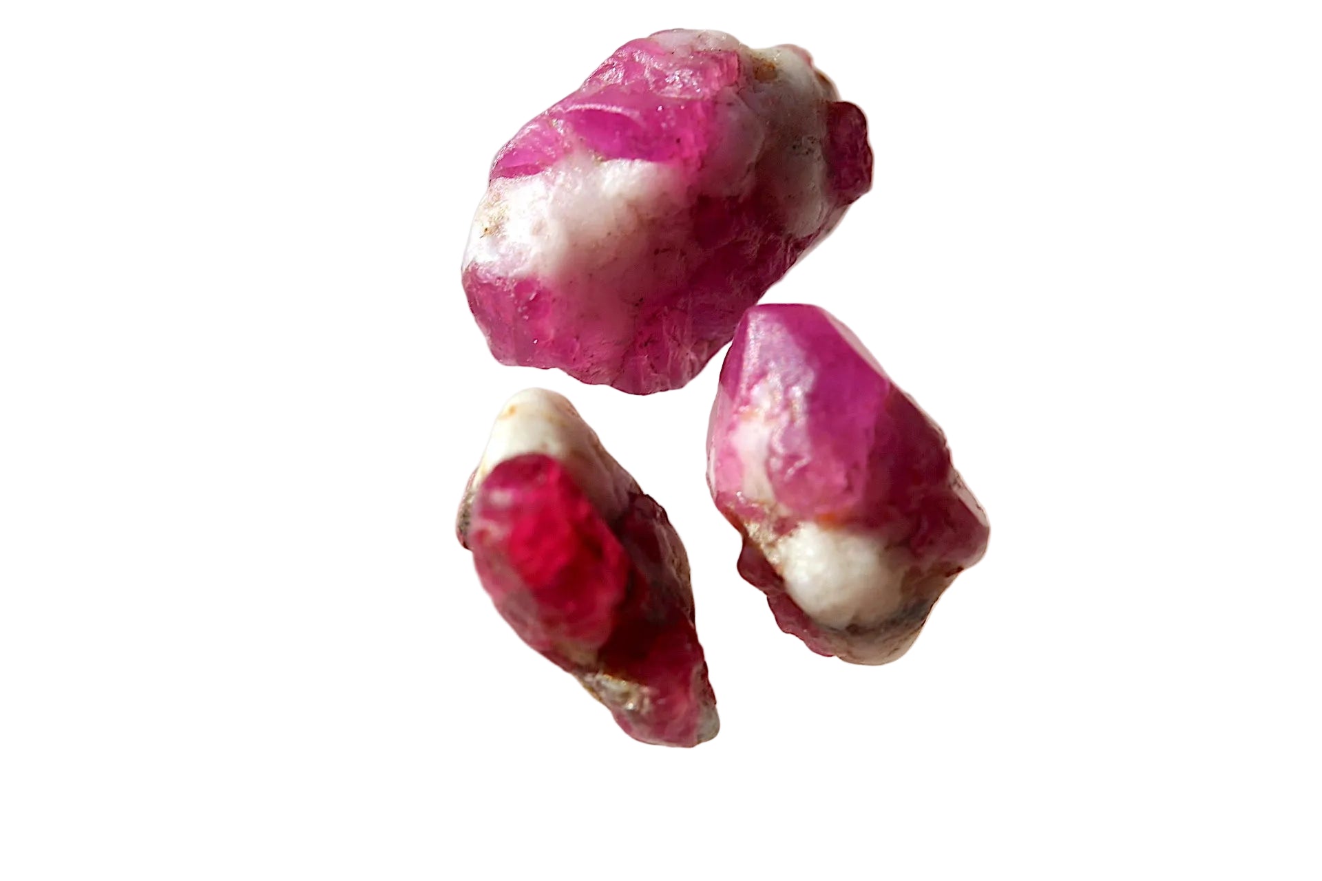 Three pink and red crystals on a light gray background