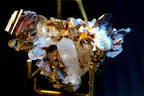 A mineral specimen featuring a large clear quartz crystal and brookite crystals