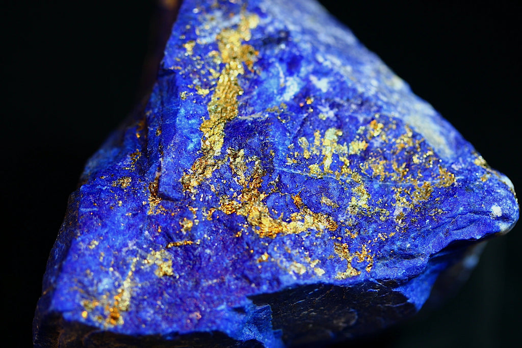 A close-up of a blue lapis lazuli crystal with prominent metallic gold pyrite