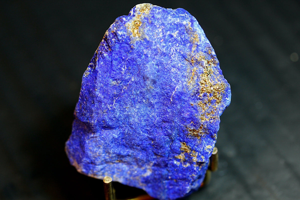 A rough blue lapis lazuli crystal specimen with prominent gold pyrite veins