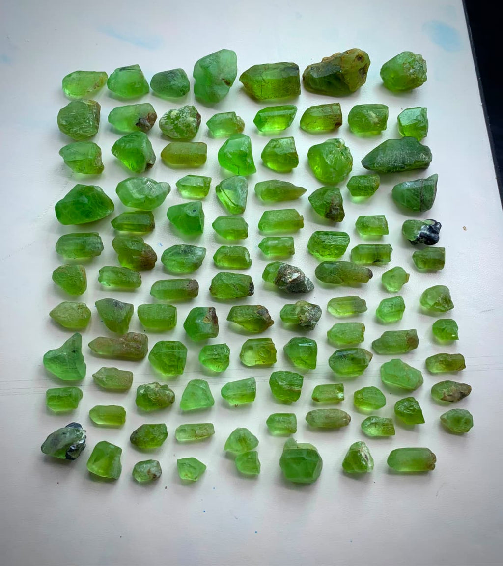 A collection of rough, uncut green peridot gemstones