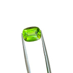 A bright green cushion-cut Peridot gemstone for making a ring