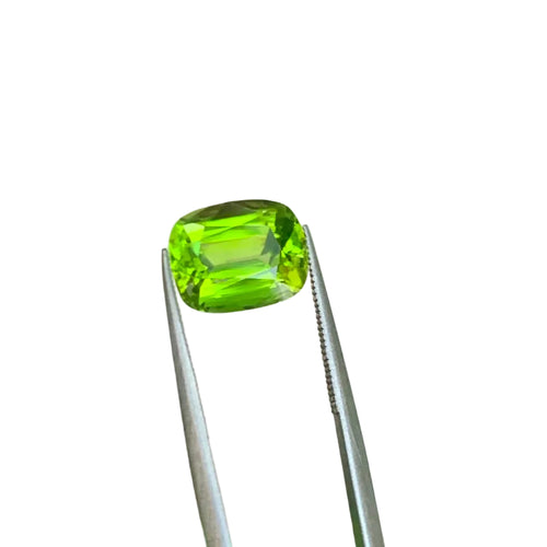 A bright green cushion-cut Peridot gemstone for making a ring
