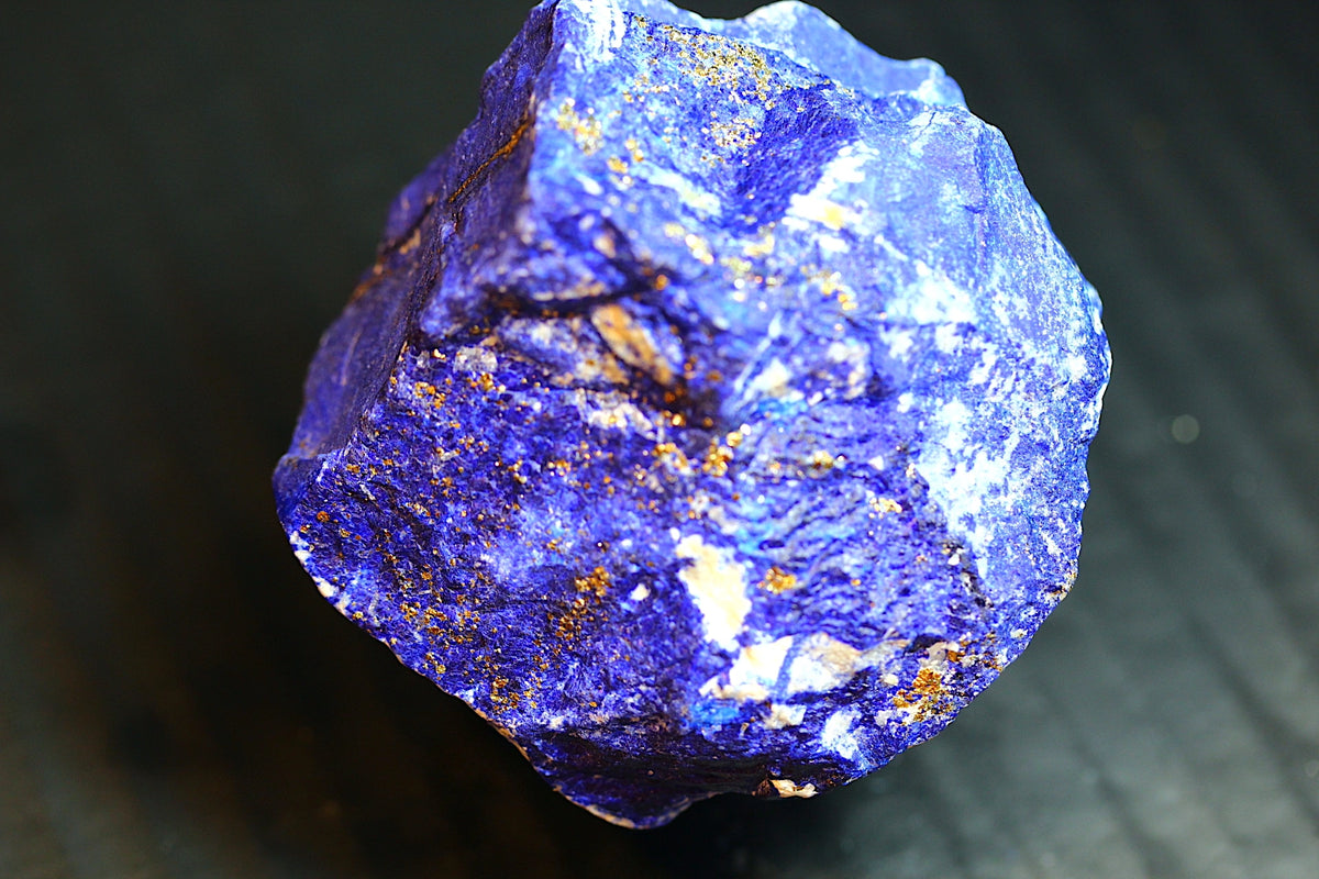 A raw, rough blue lapis lazuli crystal with visible gold pyrite inclusions