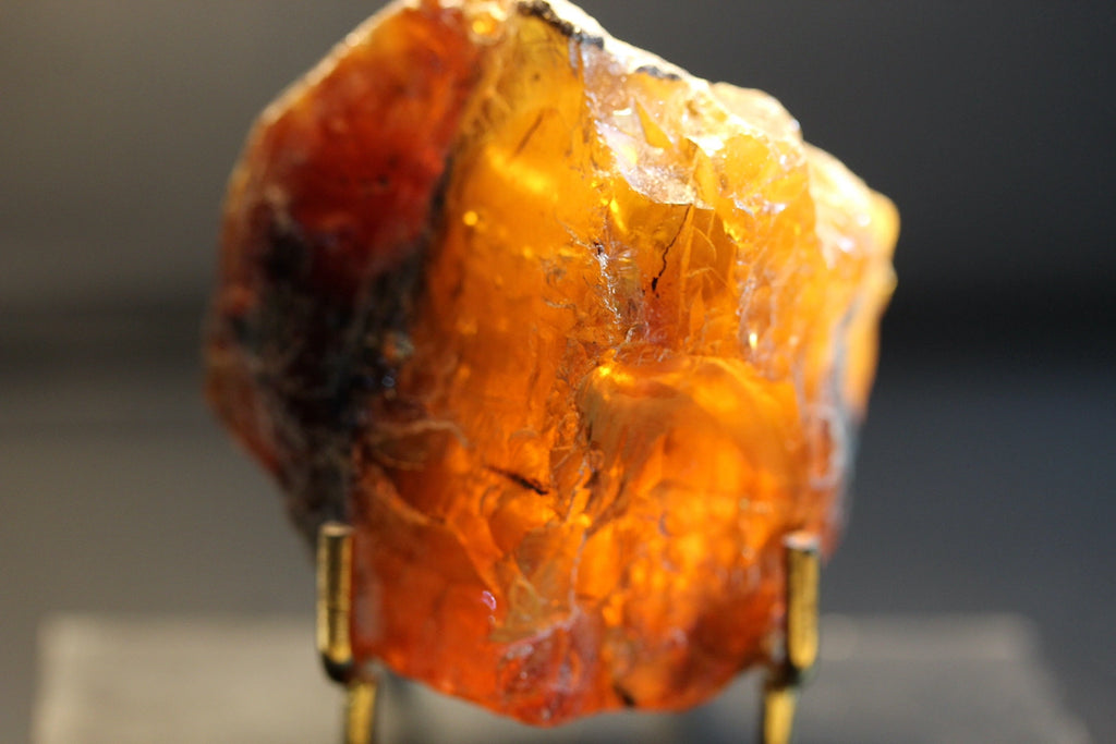 A raw, rough amber-colored gemstone or mineral specimen