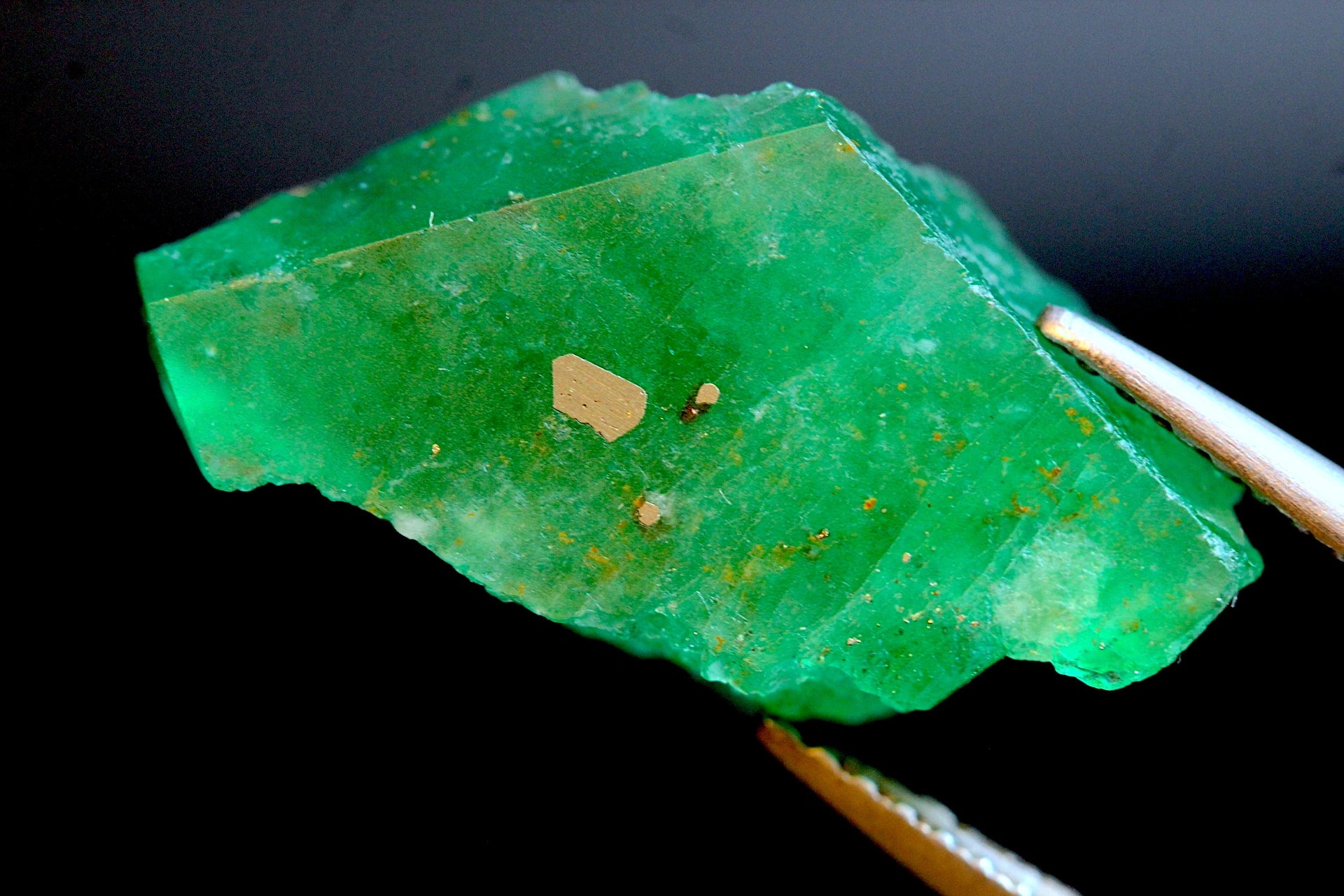 A raw, rough green emerald  gemstone with golden pyrite inclusions on surface from Swat